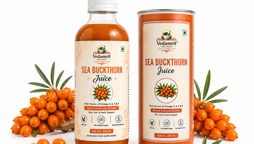A bottle and a can of Vedamrit Sea Buckthorn Juice displayed on a white background, flanked by fresh orange sea buckthorn berries and green leaves. The product packaging features a beige label with orange and black text, and the liquid inside is a translucent amber-orange color.